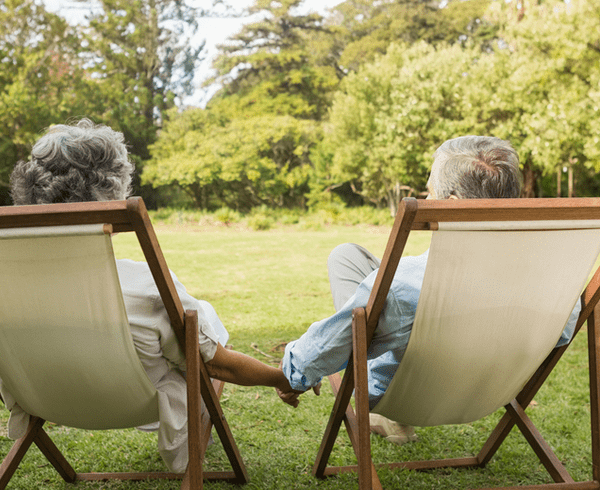 Senior couple sitting in garden holding hands