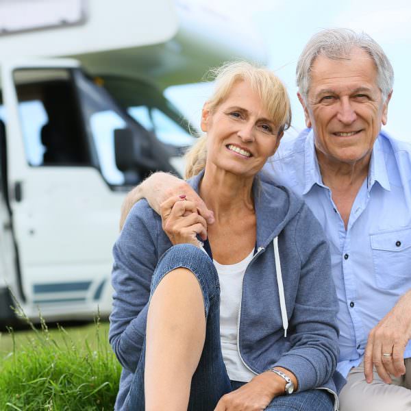 Senior couple sitting in front of camper van